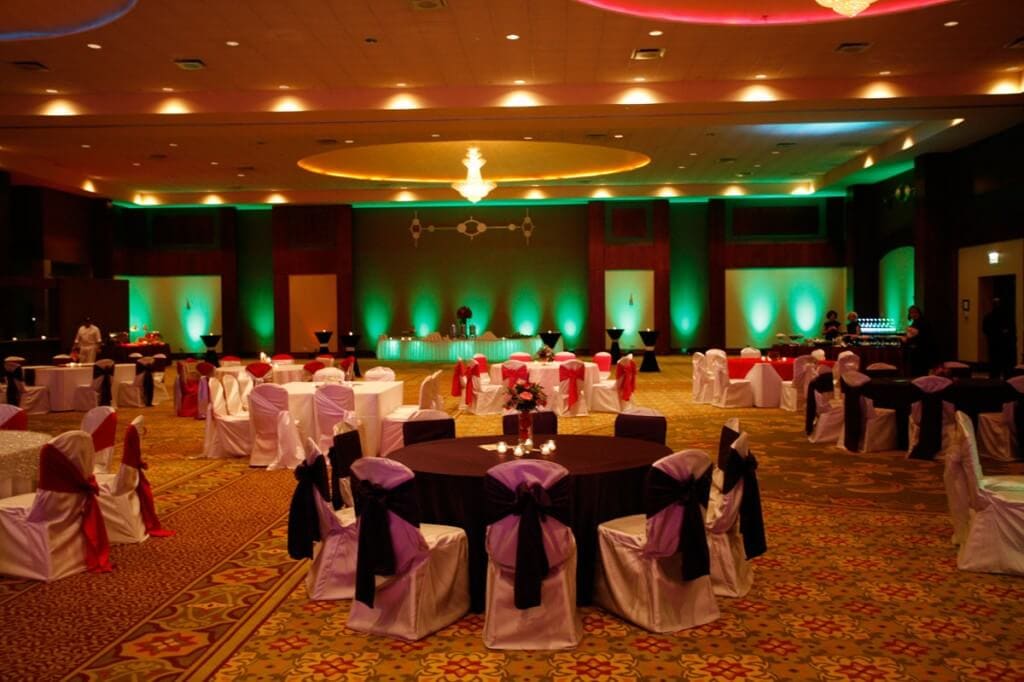 A banquet hall with round tables and green stage lighting