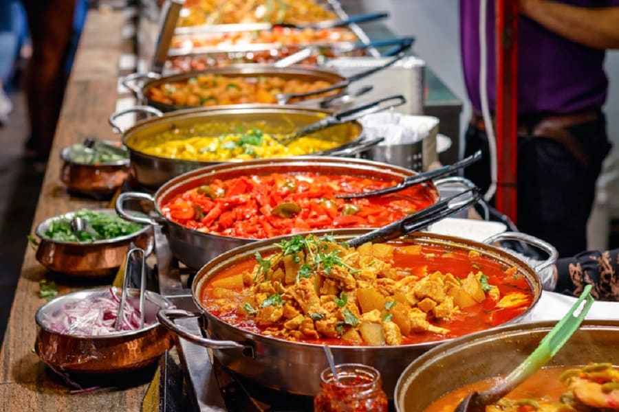 Copper serving pots filled with curries at a catering buffet