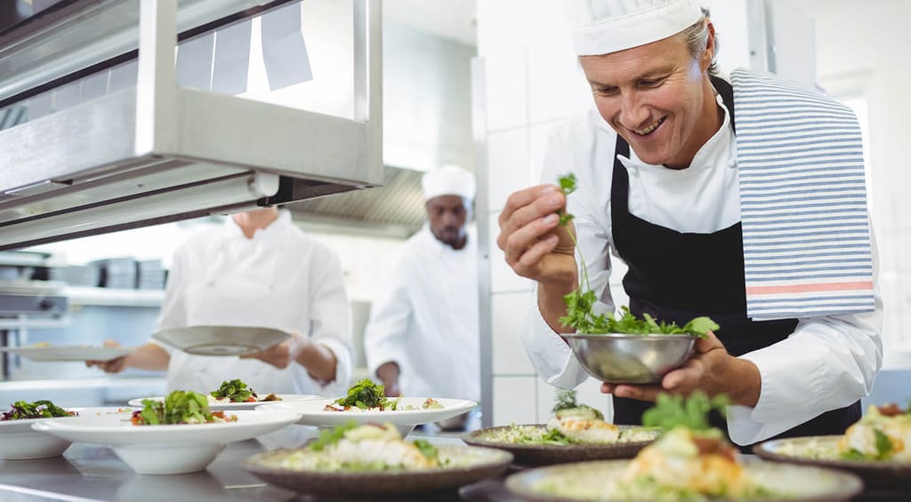A chef plating food in a restaurant kitchen